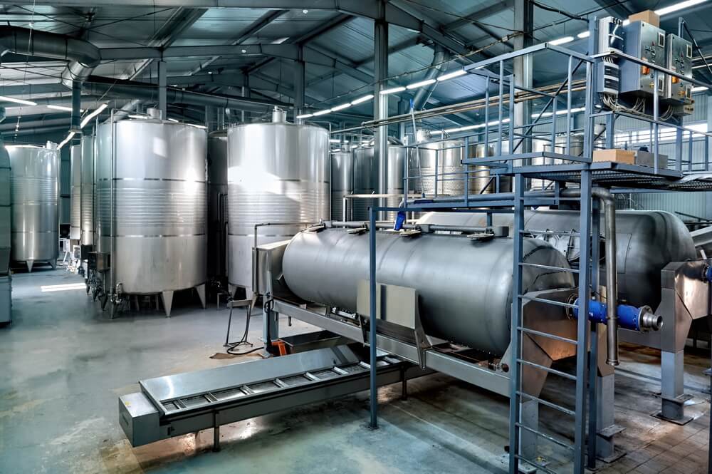 An industrial boiler and pressure vessel in a plant room, carrying an operating certificate that stays valid only while both its inspections are current