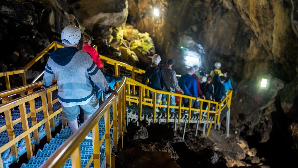 A hard-hatted crew descending yellow-railed metal walkways into a dimly lit underground space — the kind of permit-required confined space entry that demands current, role-specific training