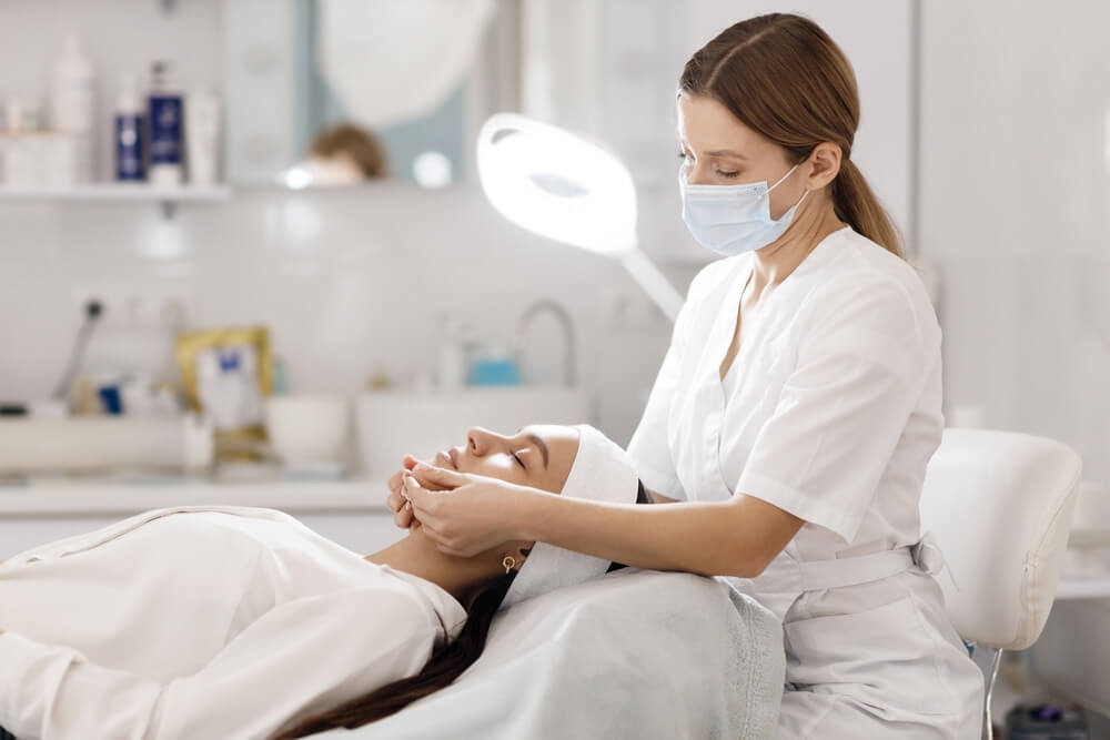 A stylist working with a client in a salon while the owner tracks the establishment license and every practitioner's individual cosmetology license renewal