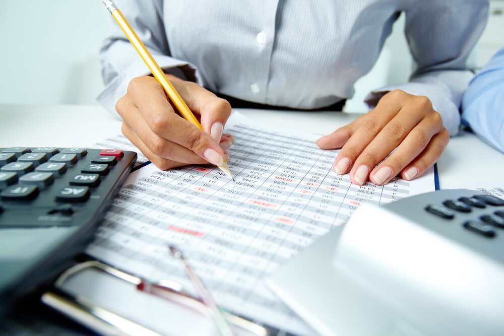 A certified public accountant reviewing financial statements while the firm tracks each CPA's license renewal and continuing professional education deadlines