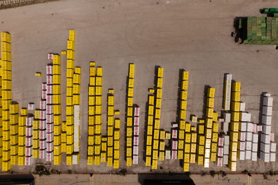 Top-down aerial view of rows of yellow and white cargo units stacked in a paved logistics depot yard