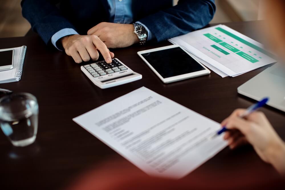 A banker and a client reviewing credit terms across a desk — where a letter of credit's expiry, latest shipment date, and presentation period are set