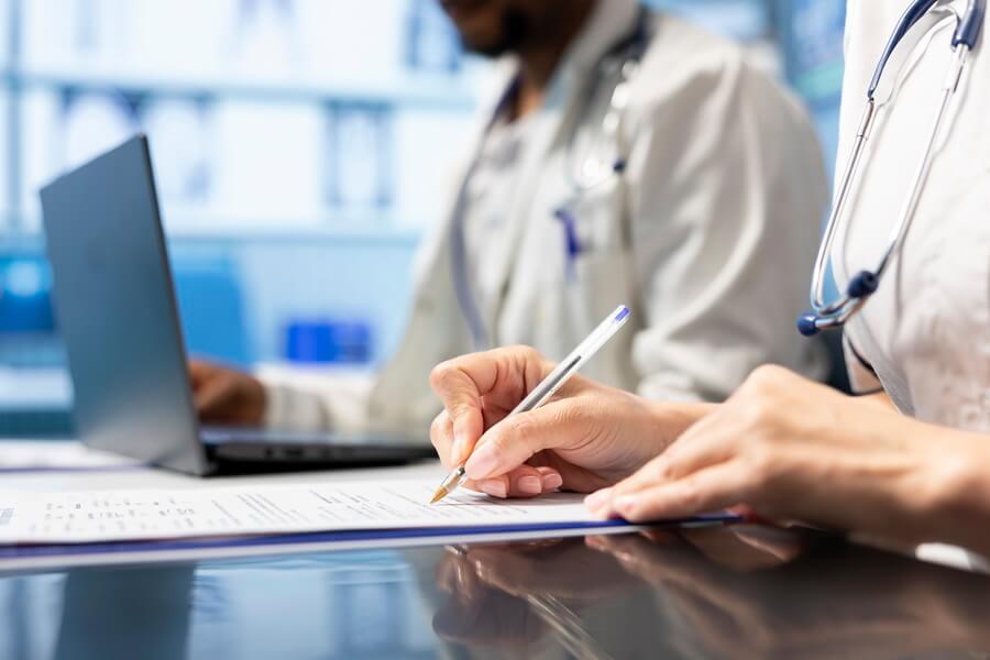 A credentialing specialist working through a provider file of re-appointment, payer, and CAQH dates alongside the underlying licenses they depend on