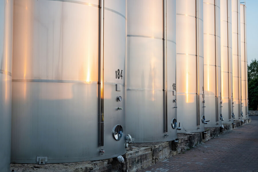 A row of numbered bulk storage tanks at a site, each one carrying its own leak detection, testing, training, and registration dates