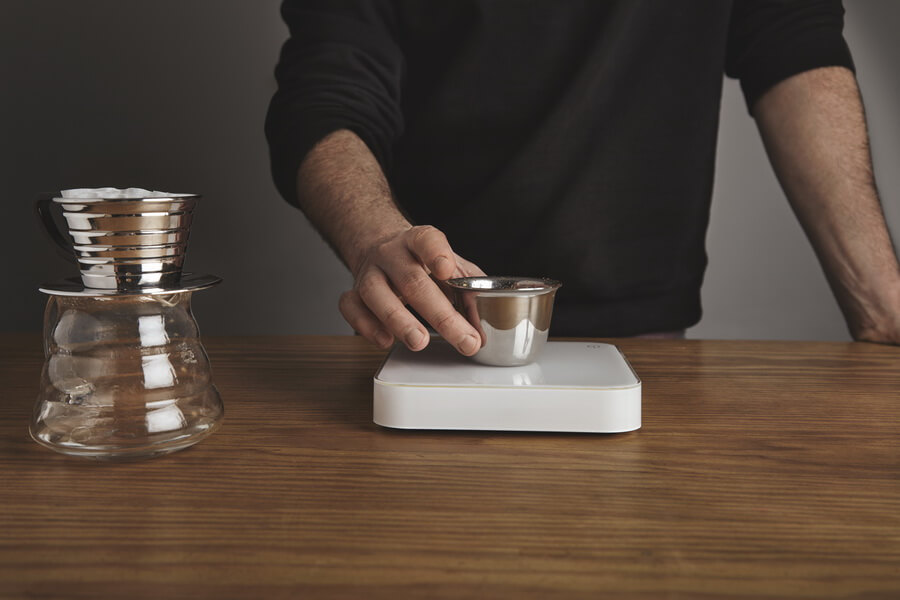 A counter scale being used to weigh product for sale behind a shop counter — the kind of device that has to be inspected and sealed as legal for trade
