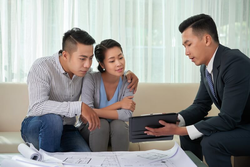 Real estate agent reviewing license documents with clients in a professional office setting